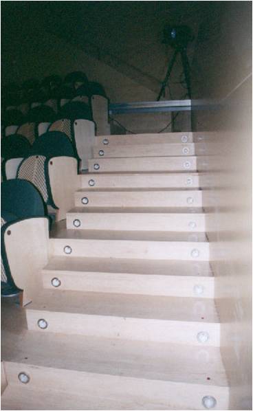 En la imagen se observa una escalera accesible. Falta pasamanos lateral y señalizar con cambio de color o textura la huella y contrahuella. Esca