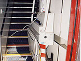 En la imagen se observa un acceso al piso superior para personas con grandes discapacidades en su movilidad, mediante plataforma montaescaleras.